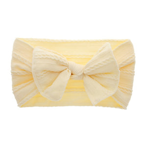 Cable knit bow in soft yellow